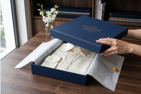 Logo thương hiệu được ép kim bạc lấp lánh trên bề mặt in hộp giấy đựng quần áo.