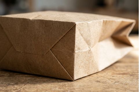 Cận cảnh chi tiết đường gấp sắc nét và mối dán đáy chắc chắn của một chiếc túi giấy kraft được sản xuất trên dây chuyền tự động.