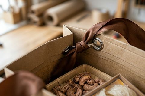 Hệ thống nẹp miệng gia cố và khuy mắt cáo kim loại bảo vệ quai xách của túi giấy cao cấp chịu tải trọng lớn.