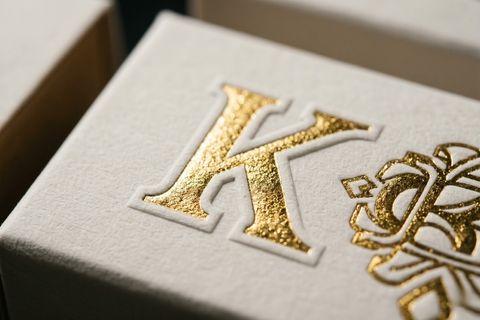 Kỹ thuật ép kim dập nổi logo trên nền giấy ivory kraft.