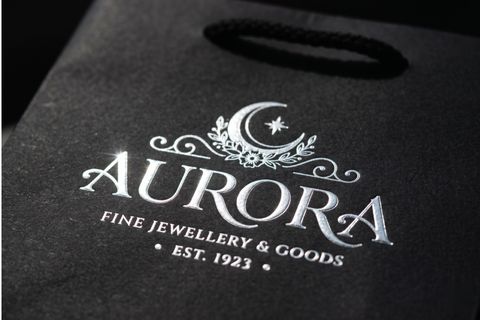 Logo thương hiệu được ép kim bạc rực rỡ trên bề mặt in túi giấy bán hàng.